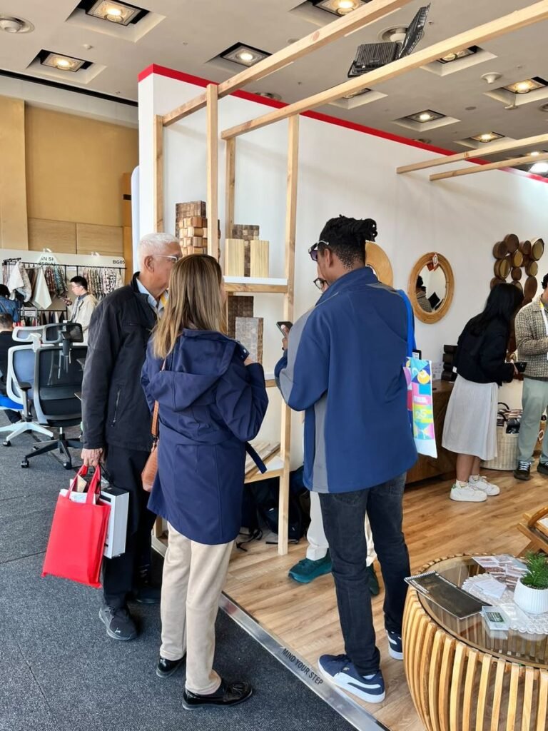 Visitors browsing coconut shell and teak wall panel samples on a timber shelf at the Indonesia Pavilion