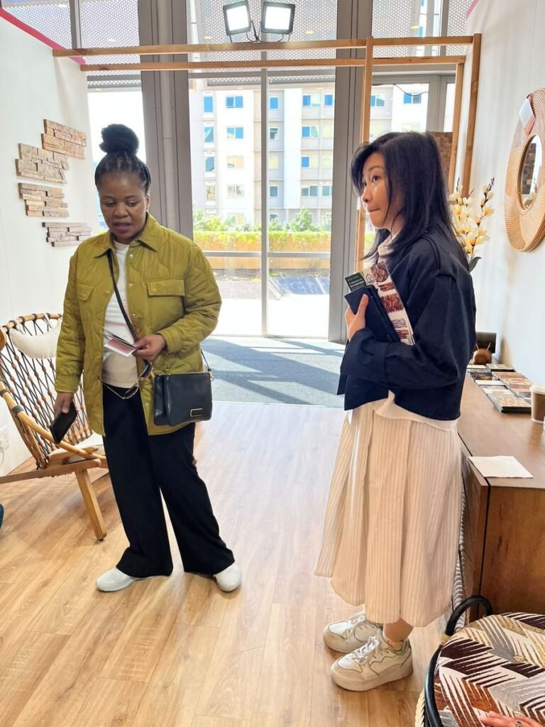 Product consultation with a visitor at the Indonesia Pavilion, teak wall cladding samples in the background